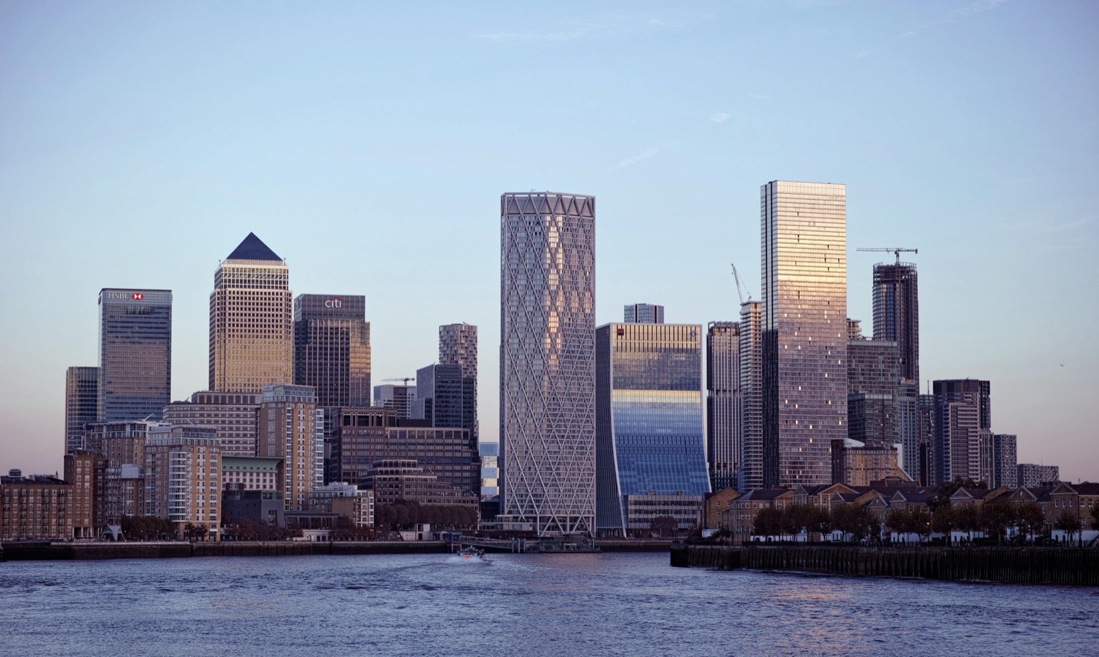 A cluster of glass residential and office towers on the riverfront at Canary Wharf, seen across the water in low winter light